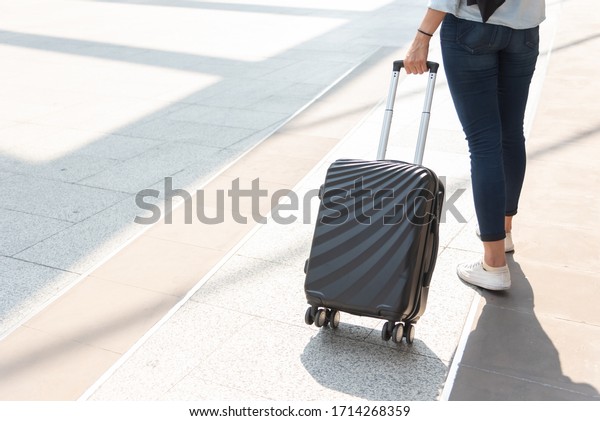 Close up woman and suitcase trolley luggage in\
airport. People and lifestyles concept. Travel and Business trip\
theme. Woman wear jeans going on tour and traveling around the\
world by alone solo girl