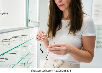 Close up of  woman taking eyeglasses from rack. Female choosing stylish prescription glasses on eyewear display stand in optical store. Vision health, blindness concept. Selective focus - Powered by Shutterstock