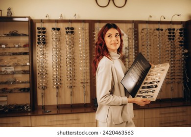 Close up of woman taking eyeglasses from rack. Female choosing stylish prescription glasses on eyewear display stand in optical store. Vision health, blindness concept. Selective focus.  - Powered by Shutterstock