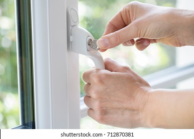 Close Up Of Woman Turning Key In Window Lock