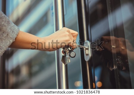 Close up of woman unlocking entrance door with a key. Person using key and locking apartment door.