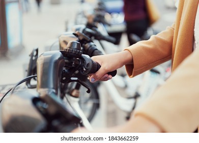 Close Up Woman In Urban Station With Electric Bicycles For Rent And Commuting Around The City To Work Leading A Healthy Lifestyle