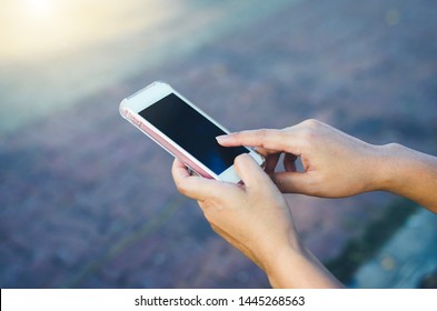 close up woman use hands typing mobile phones and touch screen working search with app devices vintage style in park with sunrise and blur nature background.
