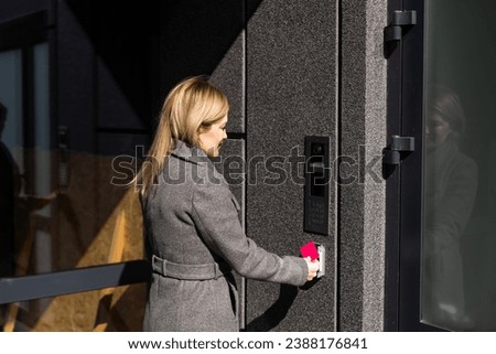 Close up of woman using card intercom at building entrance.