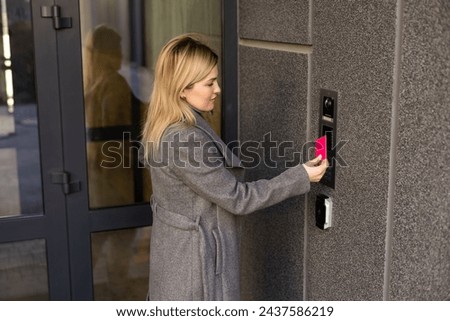 Close up of woman using card intercom at building entrance.