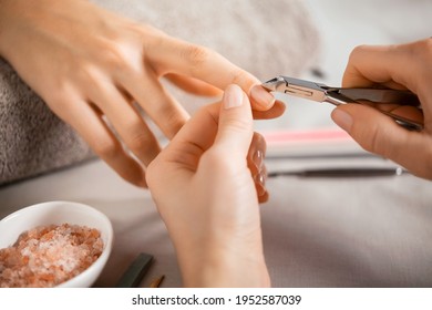 Close up of a woman using a cuticle clipper to give a nail manicure. Woman remove a cuticle nail with steel nail clipper. Manicurist using a stainless pusher for cuticle on hands during treatment.