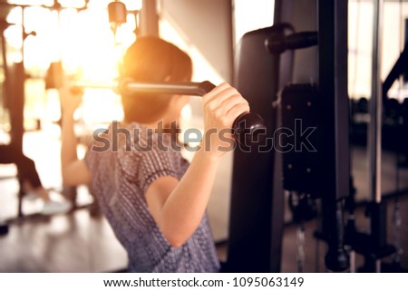 Close up woman using lat pulldown machine in gym fitness.