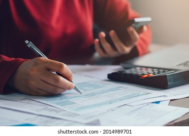 Close up woman using a pen filling form of Individual Income Tax Return, in living room at home.Expenses, account, taxes, home budget concept 