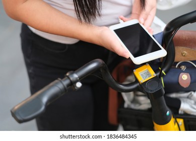 femme en gros plan utilisant un téléphone pour scanner le code QR afin de déverrouiller le vélo partagé