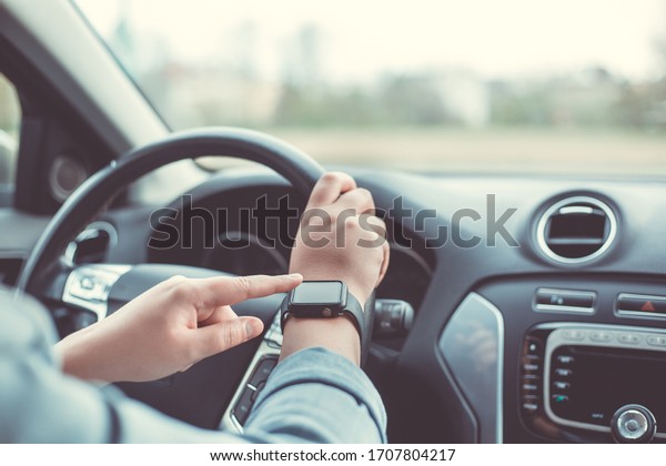 Close up of woman using smart watch during\
driving her car, transport\
concept