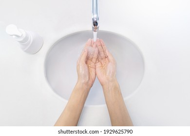 Close Up Of Woman Washing Her Hands Under Running Water For Protection, And Soap Pressed Bottle Sinks Top View.
