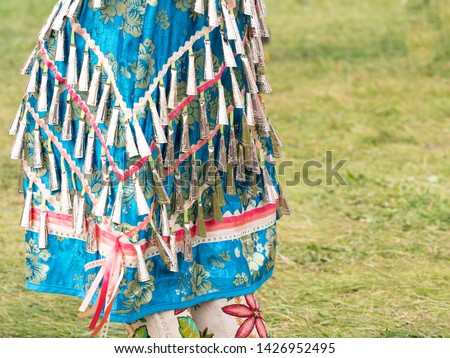 Close up of a woman wearing a blue brocade jingle bead dress and beaded leggings photographed at a pow wow in Montana.