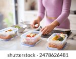 Close Up Of Woman Wearing Fitness Clothing At Home In Kitchen Making Healthy Meals For The Freezer