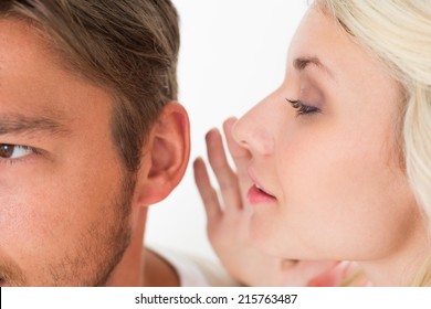 Close Up Of A Woman Whispering Secret Into A Man's Ear Over White Background