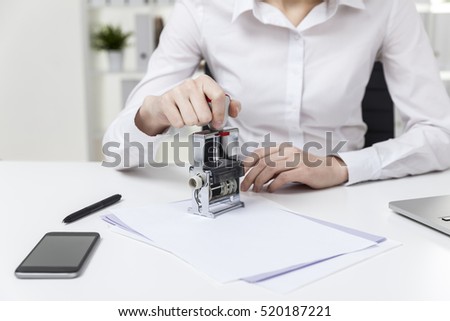 Close up of a woman in white blouse who is sitting in the office and stamping a treaty. Concept of notary work
