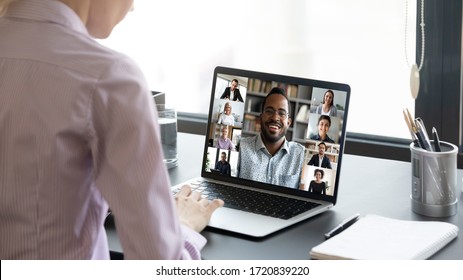 Close up of woman worker sit at desk talk speak on video call with multiracial colleagues or friends, female employee have online briefing with international team, engaged webcam conference at home