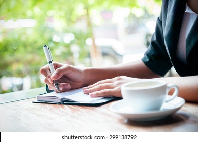 close up of woman writing journal and cup of coffee 