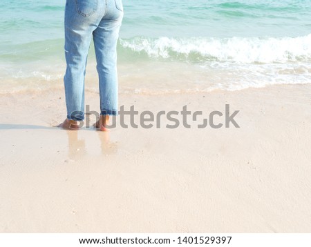 Close up of woman's feet walking on the sand beach and soft wave at seaside