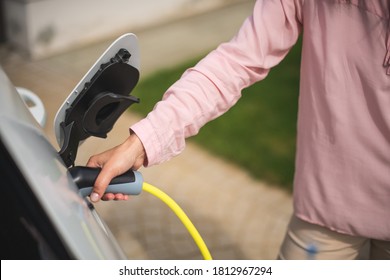 Close Up Of A Woman's Hand Charging A Electric Car At A Charging Station