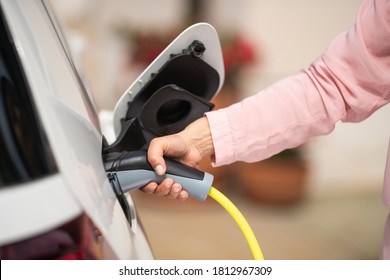 Close Up Of A Woman's Hand Charging A Electric Car At A Charging Station