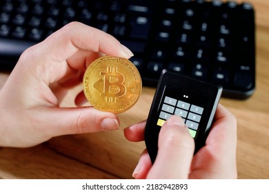 Close up womans hand holding bitcoin and cryptocurrencey hardware cold wallet on keybord background. Secure cryptocurrency storage.