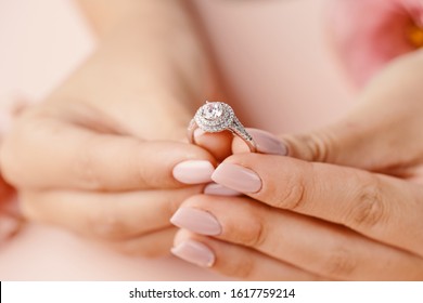 Close up of woman's hand holding elegant diamond ring with feather and pink background with flowers. Diamond ring. Jewelry. - Shutterstock ID 1617759214