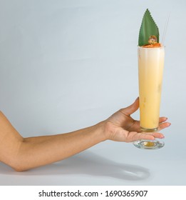 Close Up Of A Woman's Hand Holding A Glass Of Tropical Pina Colada Cocktail On White Background With Copy Space. Summer Time Vacation Concept.