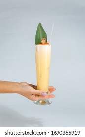 Close Up Of A Woman's Hand Holding A Glass Of Tropical Pina Colada Cocktail On White Background With Copy Space. Summer Time Vacation Concept.