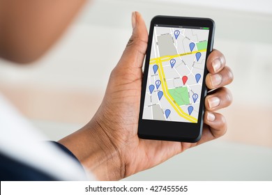 Close Up Of Woman's Hand Holding Mobile Phone With Various Location Mark On Map