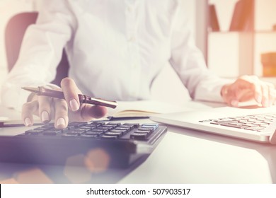 Close Up Of Woman's Hand On Her Calculator's Keyboard. The Second Hand In On Laptop Touchpad. Concept Of Accountant's Work. Toned Image