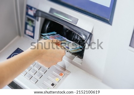 Close up of a woman's hand withdrawing cash, euro bills from the ATM bank machine. Finance customer and banking service concept