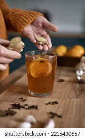 Close up of woman's hands adding ginger to the tea 
