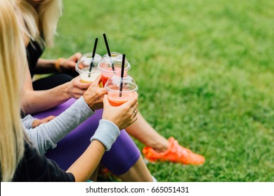 Close Up Of Woman's Hands Holding Three Plastic Cup With Smoothie Breakfast Takeaway Juice To Go After Morning Run In Summer Park Over Green Grass. Generation, Sport, Friendship And Healthy Concept