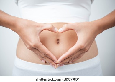 Close up of woman's hands made heart on belly isolated on white background.health care concept. - Shutterstock ID 583399804