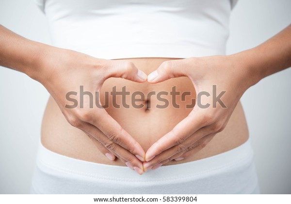 Close up of woman\'s hands\
made heart on belly isolated on white background.health care\
concept.