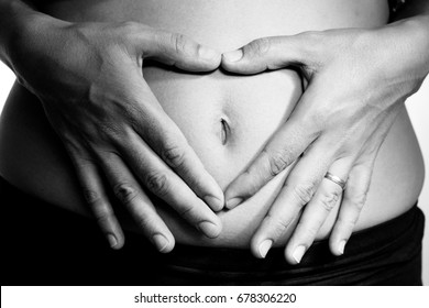 Close Up Of Woman's Hands Making A Heart Shaped Symbol Over The Belly Button Symbolizing Pregnancy 