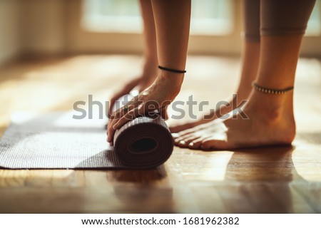 Close up of a womans hands is rolling up exercise mat and preparing to doing yoga. She is exercising on floor mat in morning sunshine at home. Foto d'archivio © 