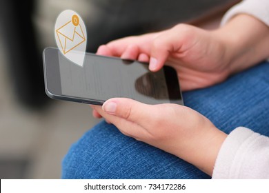 Close Up Of Woman's Hands Scrolling The Black Smart Phone And Reading All The E-mails To Reach Inbox Zero, Against Blurred Background