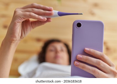 Close up of a woman's hands taking her basal temperature