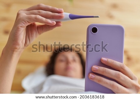 Close up of a woman's hands taking her basal temperature