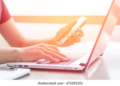 Close Up of woman's hands using mobile phone and laptop computer business with blank copy space screen for your business advertising text message or content, business in the morning light.