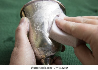 Close Up Of Woman's Hands Using Sponge To Polish Tarnish Off Silver Goblet.