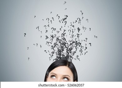 Close Up Of Woman's Head. There Are Little Black Question Marks Escaping It. Gray Wall Background. Concept Of A Challenging Issue