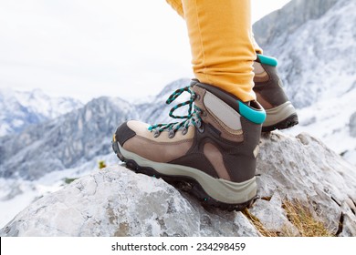 Close up of womans legs in heavy hiking boots standing on top of mountain
