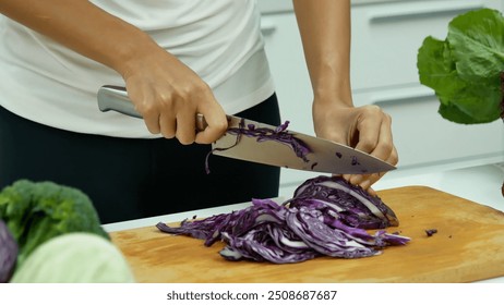 Close up Women hand cutting purple cabbage prepare fruit vegetables green bell pepper carrot tomato at home kitchen. Crop Woman hands use knife cut purple cabbage wooden cutting board vegan healthy - Powered by Shutterstock