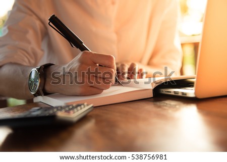 Close up women hand on writing on notebook and work with calculator