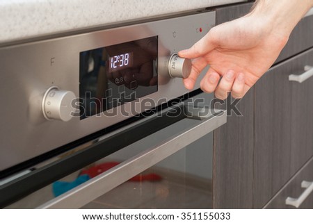 Close Up Of Women Hand Setting Temperature Control On Oven
