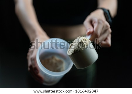 Close up of women with measuring scoop of whey protein and shaker bottle, preparing protein shake. 商業照片 © 