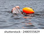 Close up of a women swimming in open water wearing an orange safety floatation in the Great South Bay in Babylon Long Island.