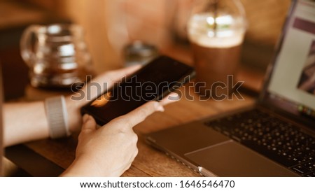 Close up of women's hands holding cell telephone with blank copy space scree for your advertising text message or promotional content, women watching video on mobile phone during coffee break 